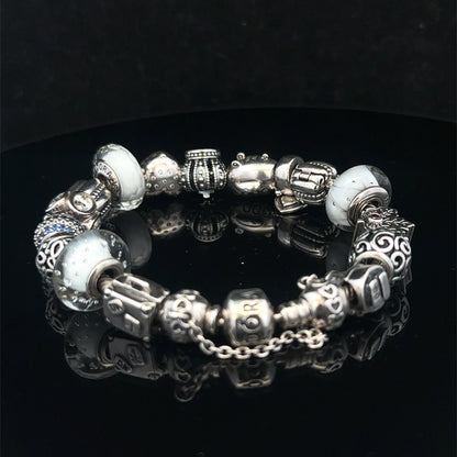 Silver Pandora-style charm bracelet by Reeves and Sons with intricate links and decorative charms, weighs 69.8g.