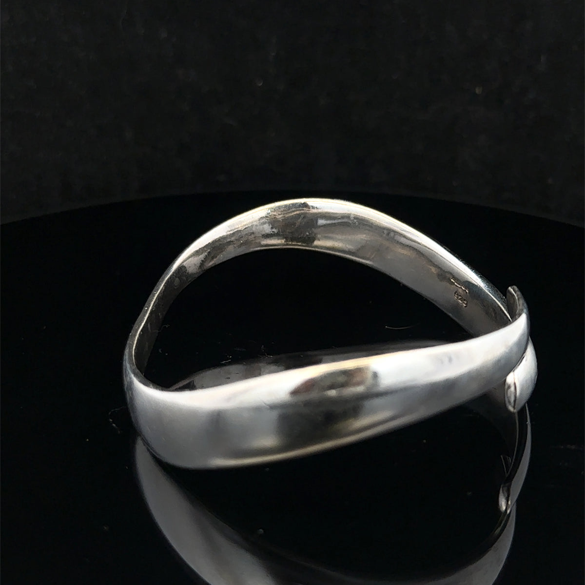 Silver bangle by Reeves and Sons weighing 45.1g, showcasing a smooth, polished design with intricate details.