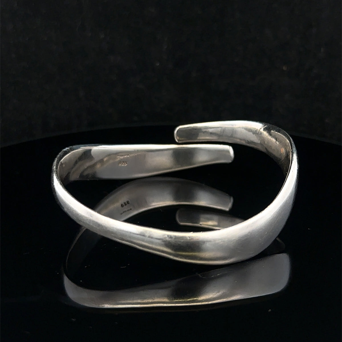 Silver bangle weighing 45.1g from Reeves and Sons, shiny jewelry piece with smooth, rounded design visible in the image.