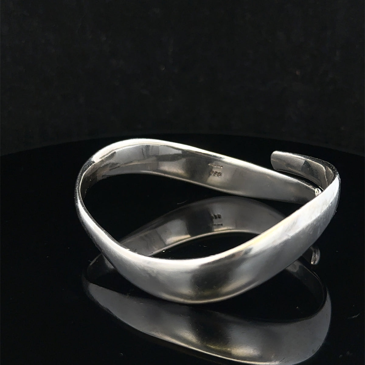 Silver bangle weighing 45.1g from Reeves and Sons, featuring a smooth, polished design with intricate detailing visible in the image.