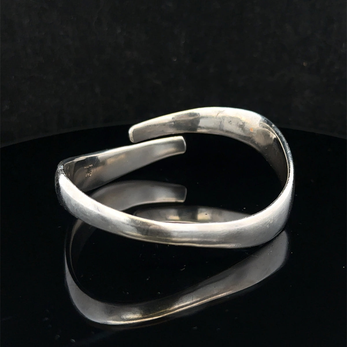 Silver bangle weighing 45.1g by Reeves and Sons, featuring a sleek, polished design with a smooth, rounded surface.