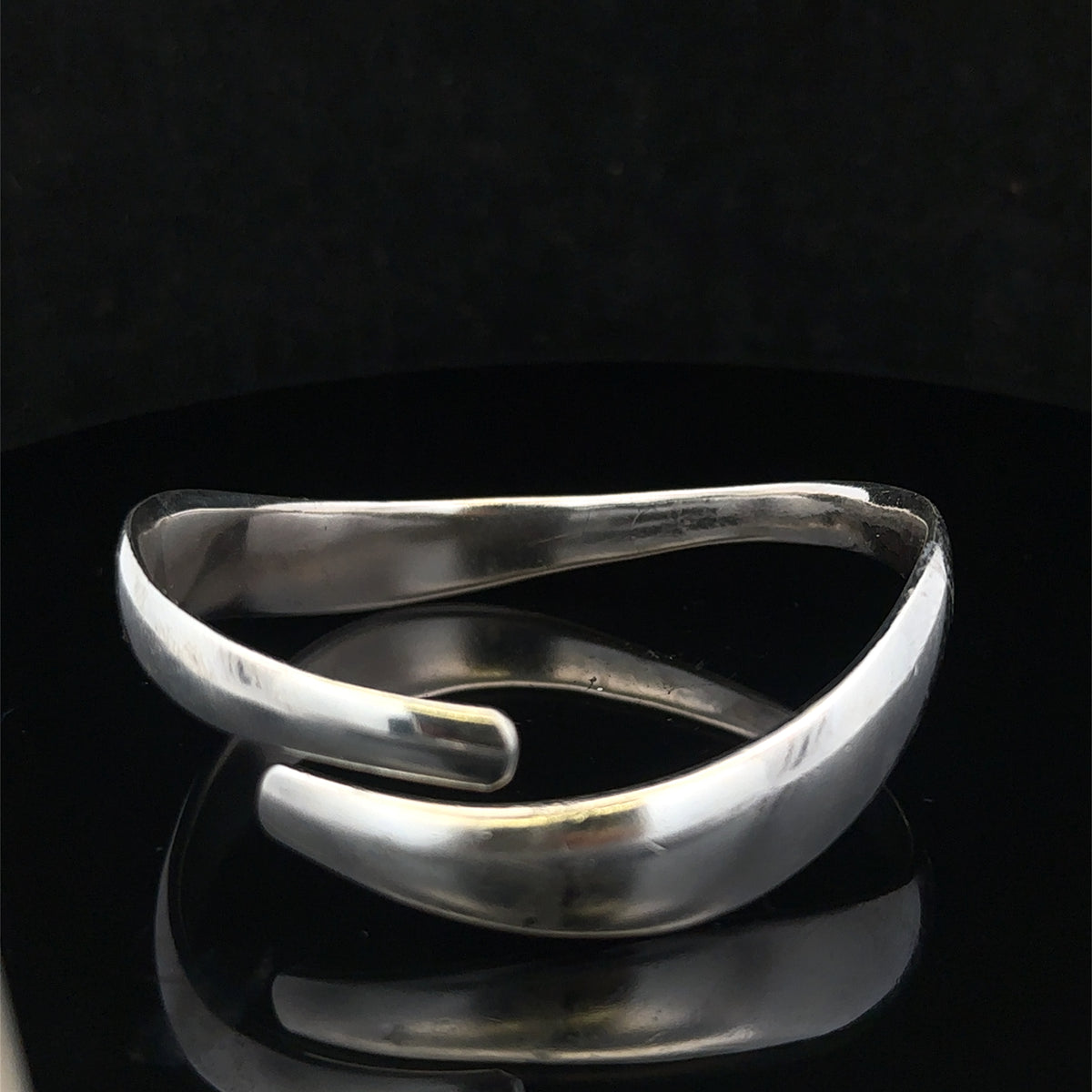 Silver bangle weighing 45.1g from Reeves and Sons, showcasing a polished, sleek jewelry piece with intricate details.