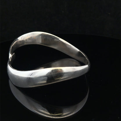 Silver bangle by Reeves and Sons weighing 45.1g, featuring a sleek, polished design with intricate detailing.