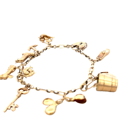 9ct yellow gold charm bracelet by Reeves and Sons, 16.3g weight, featuring multiple dangling charms