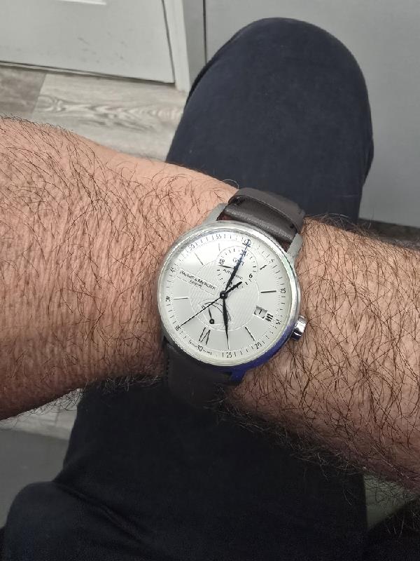 Baume & Mercier GMT automatic dual time power reserve watch with black dial and stainless steel case.