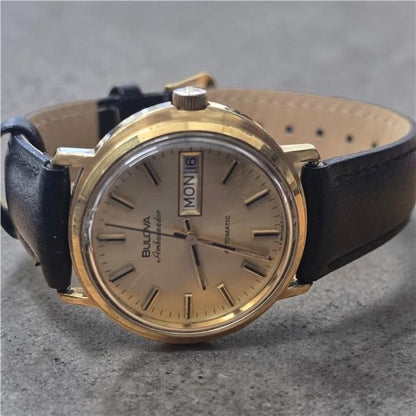 Bulova plated automatic watch with a sleek design, weighing 44.9g, featuring a round dial and metal bracelet.