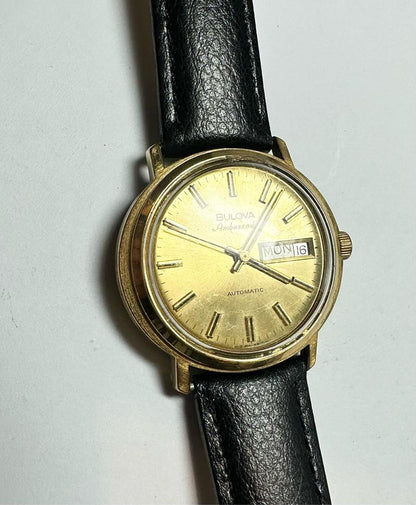 Bulova plated automatic wristwatch with a sleek silver dial and stainless steel band, weighing 44.9g, showcasing elegant design.