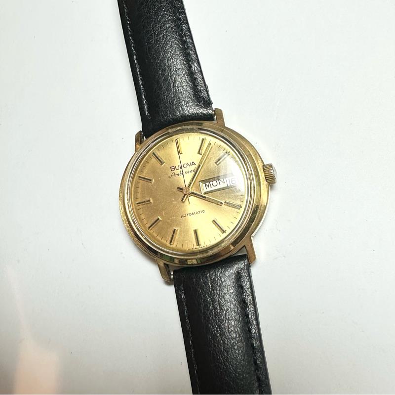 Bulova plated automatic watch with a sleek design, weighing 44.9 grams, featuring a stainless steel band and classic dial.
