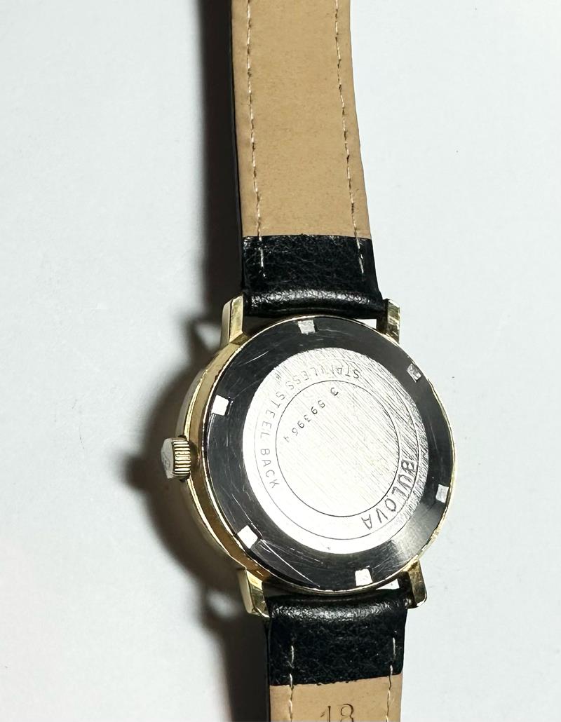 Bulova plated automatic watch with stainless steel bracelet, featuring a sleek round dial and visible movement, weighing 44.9g.