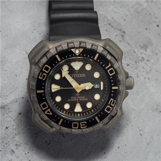 Citizen Eco-Drive titanium divers watch showing black dial, stainless steel strap, and rotating bezel.