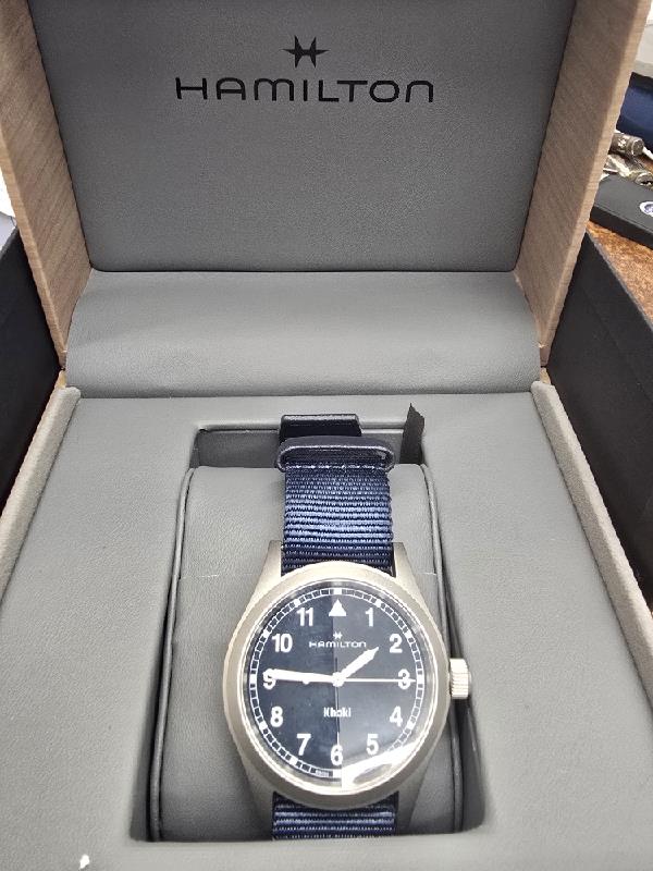 Hamilton Khaki Watch Age 2025 with black dial, stainless steel case, and leather strap, showcasing a sleek, modern design.