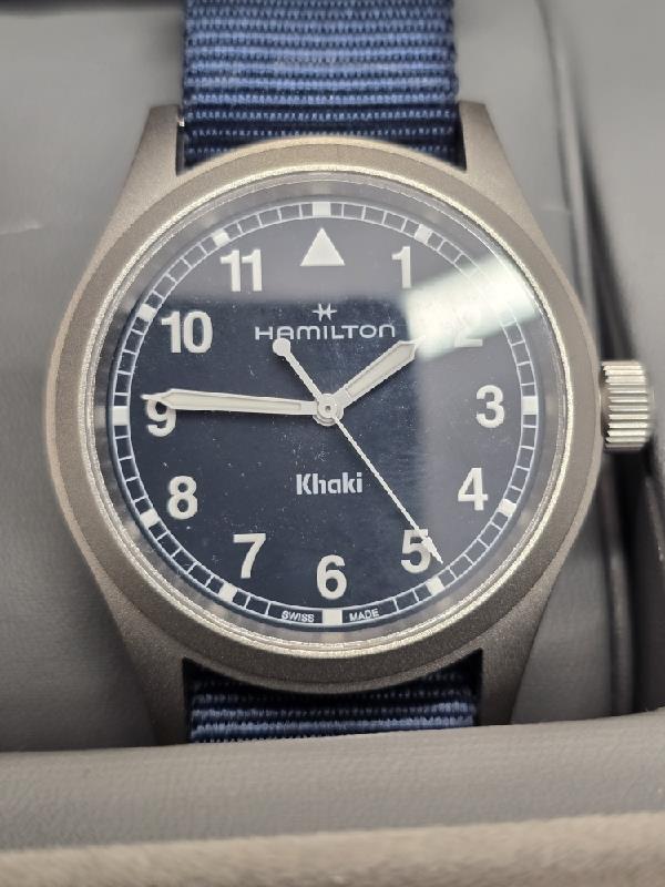 Hamilton Khaki Watch Age 2025 with black dial, stainless steel case, and leather strap, displayed on a neutral background.