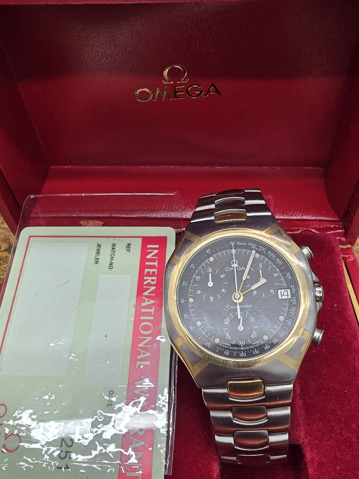 Omega Seamaster Polaris Chronograph watch with boxed packaging and authenticity card, featuring a stainless steel bracelet and blue dial.