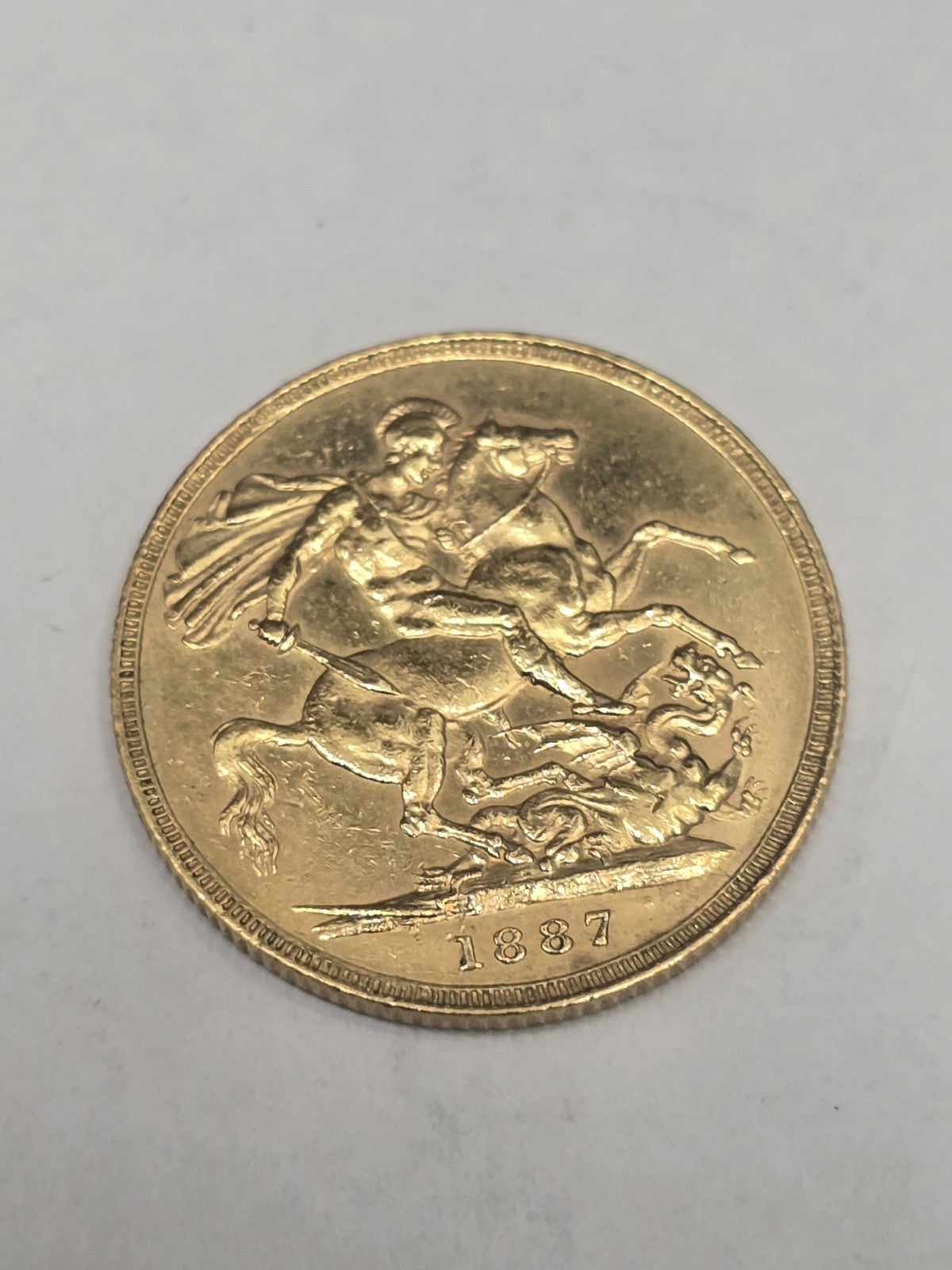 1887 Reeves and Sons full sovereign coin, 8g gold coin with detailed historic design and engraved inscriptions.