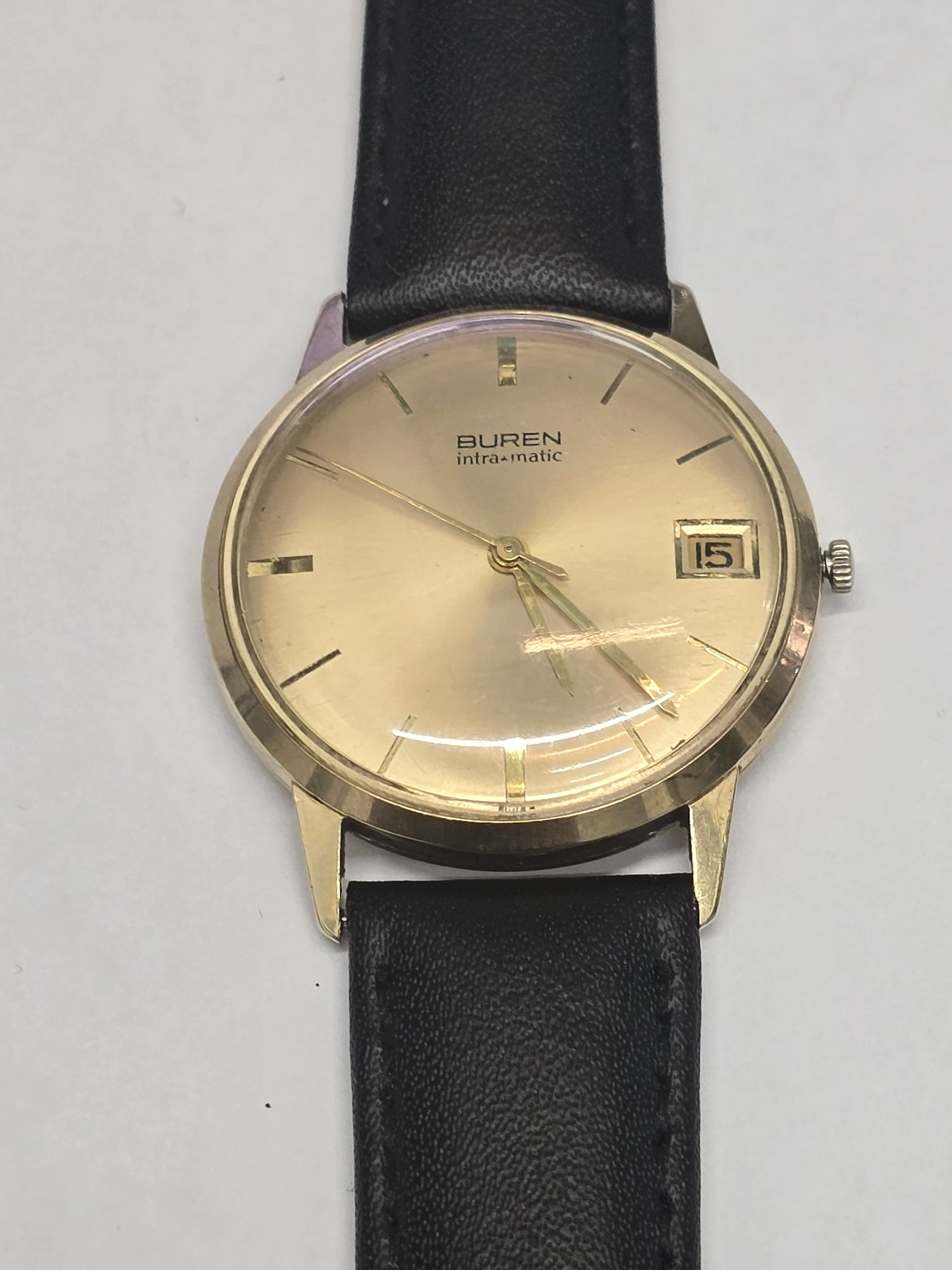 Vintage 9ct yellow gold Buren Intra-Matic automatic men's watch with Swiss craftsmanship, classic design, and leather strap.