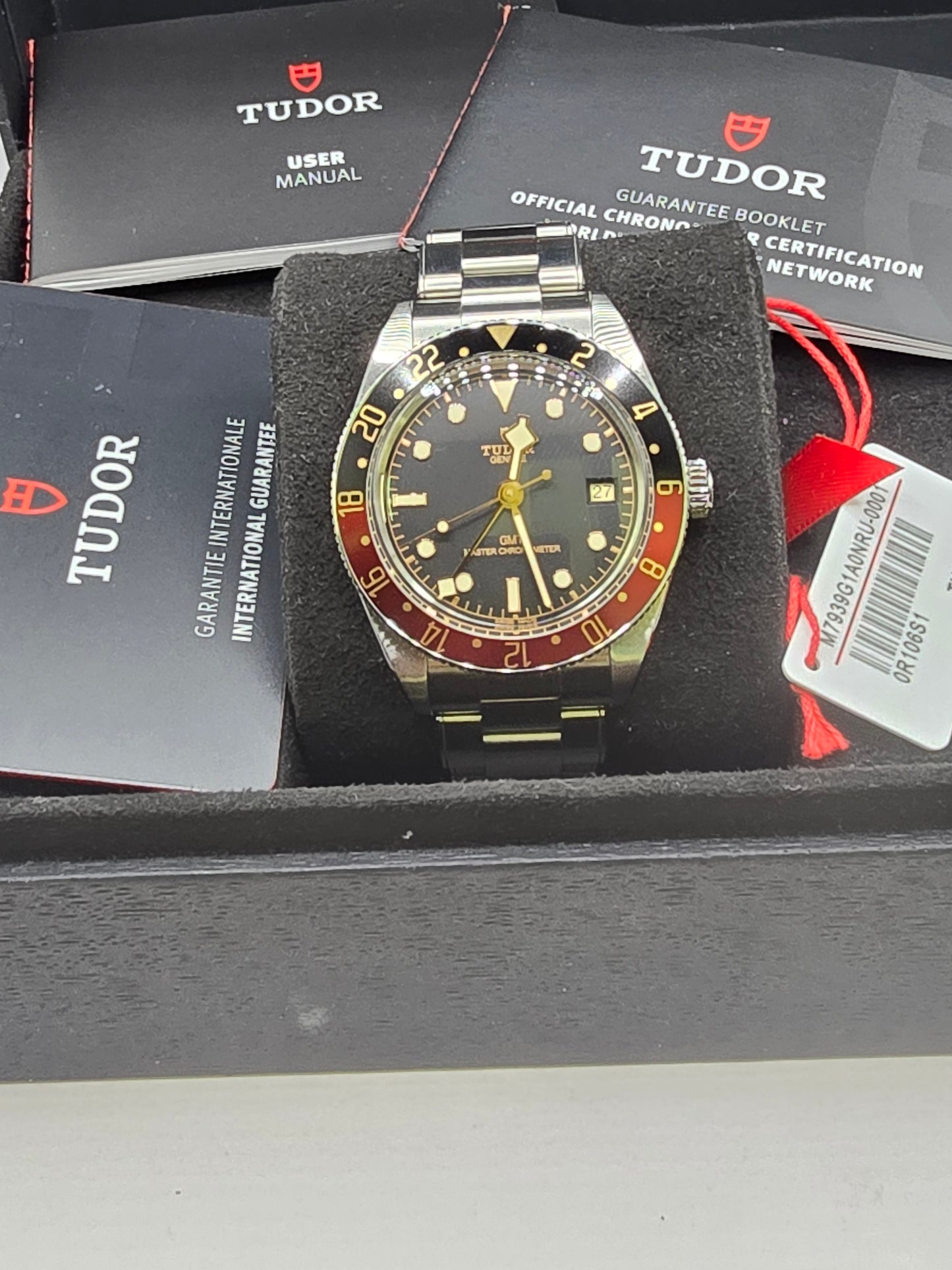 Tudor Black Bay 58 GMT Coke fullset watch from 2024 with black and red bezel, stainless steel bracelet, displayed on a watch stand