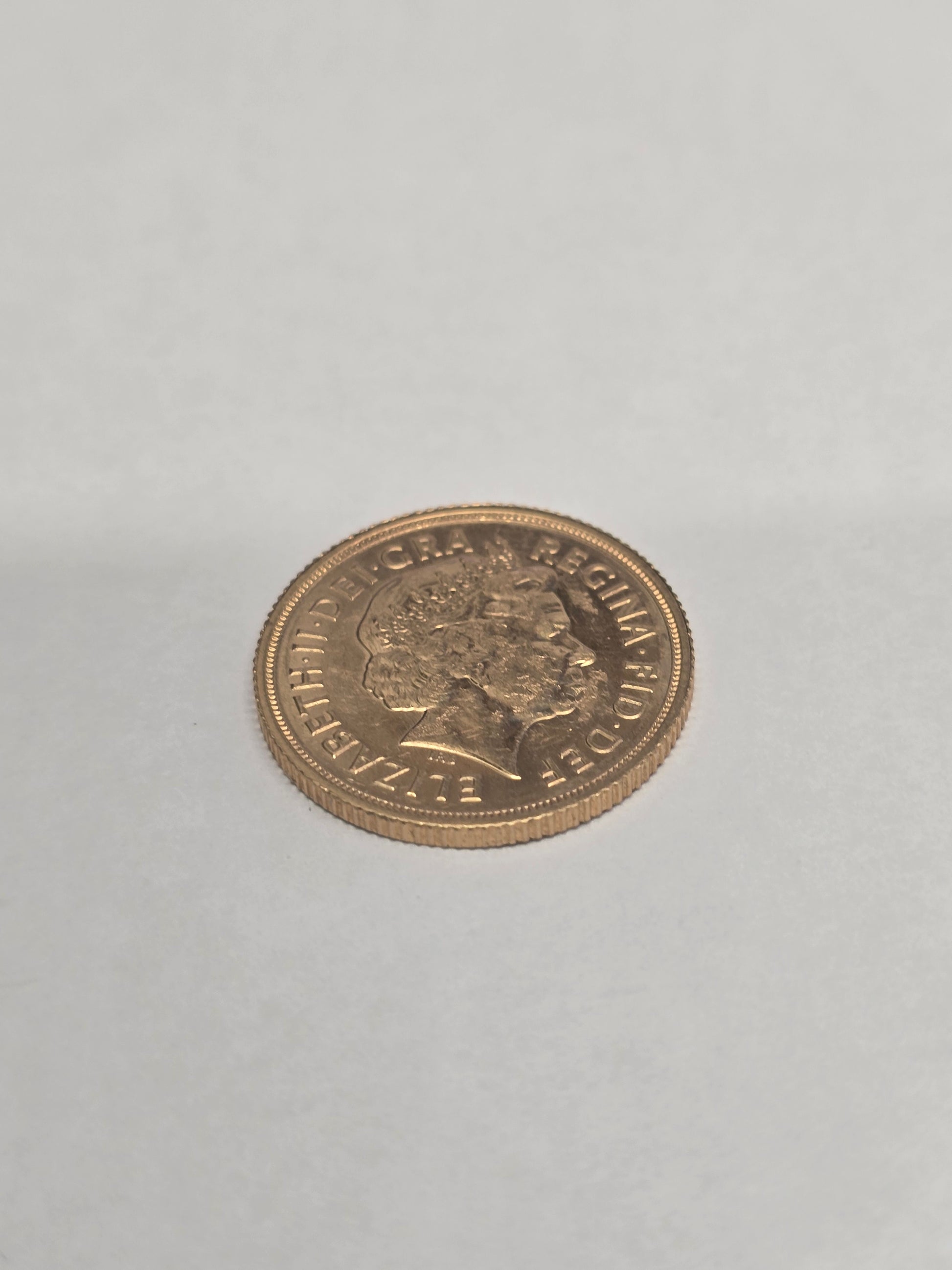 2012 Reeves and Sons full sovereign coin showing detailed portrait and inscriptions on gold-colored metal surface.