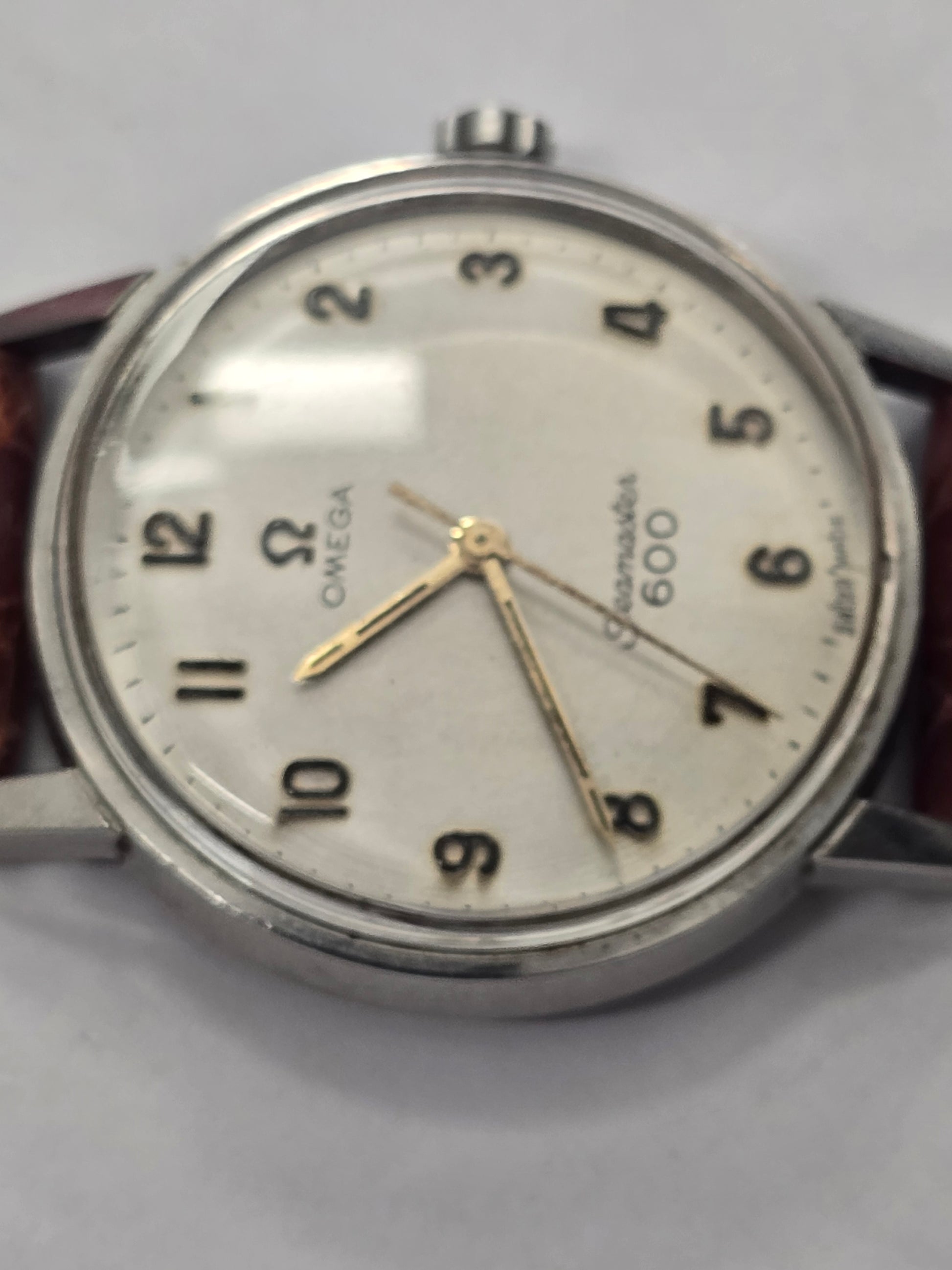 Vintage Omega Seamaster 600 Swiss-made watch with brown leather strap, featuring a classic round dial and stainless steel case.