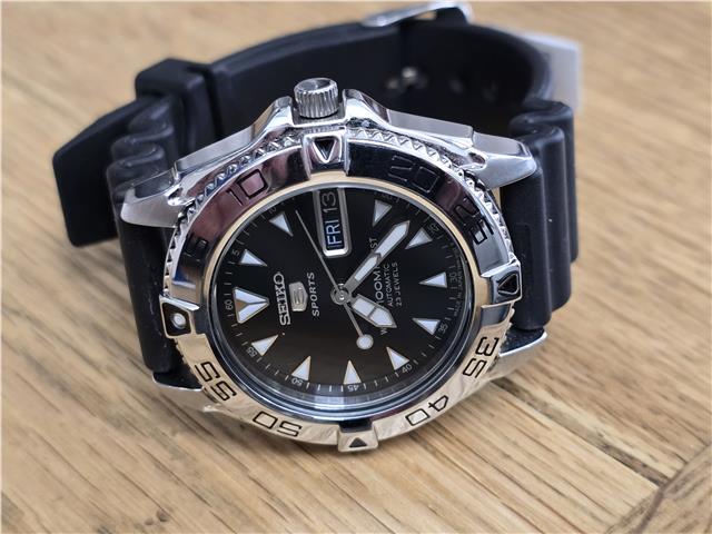 Seiko 5 Sports automatic watch with boxed papers, showcasing its black dial, stainless steel band, and classic design.