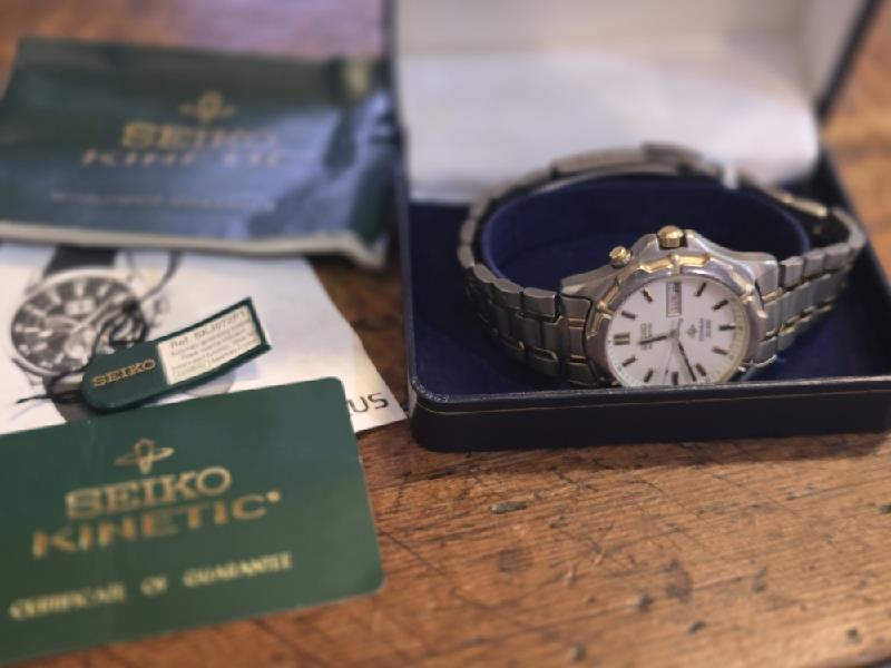 Seiko Kinetic Titanium SQ100 wristwatch with black dial and silver stainless steel strap, showcasing a sleek and modern design.