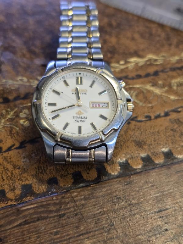 Seiko Kinetic Titanium SQ100 watch with black dial and silver strap, showcasing a sleek, modern design and precise timekeeping.