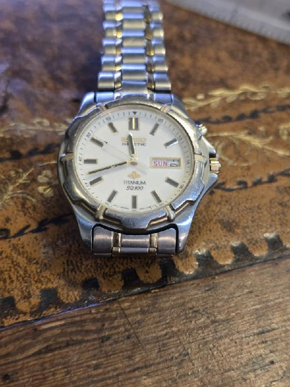 Seiko kinetic titanium SQ100 watch with black dial and silver band, showcasing a sleek modern design.