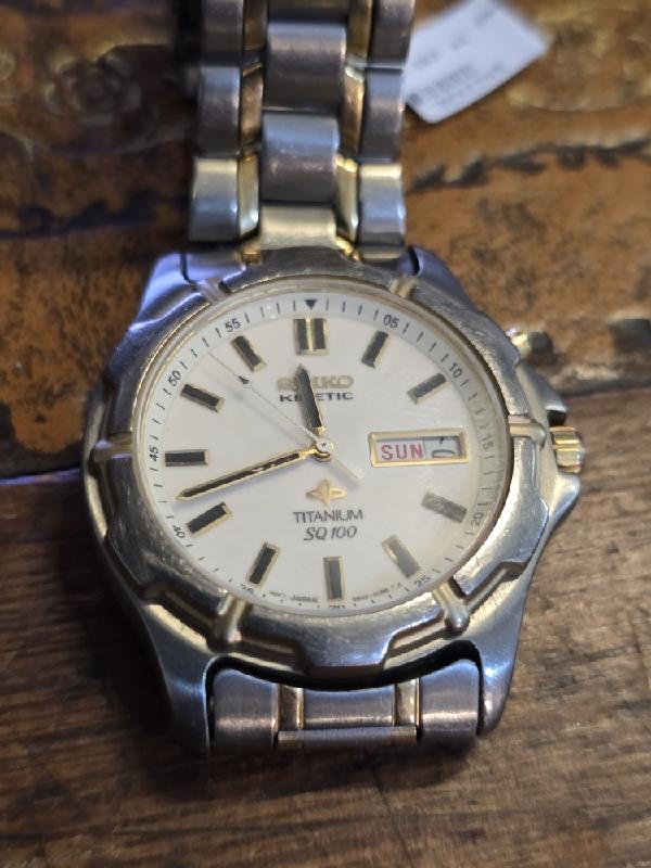 Seiko Kinetic Titanium SQ100 watch with black dial and stainless steel band, showcasing elegant design and precise timekeeping.