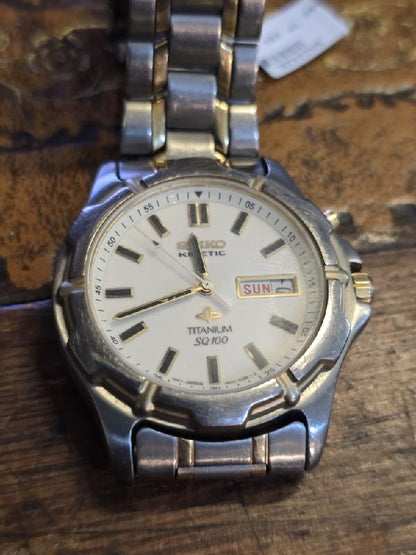 Seiko Kinetic Titanium SQ100 watch with black dial and stainless steel band, showcasing elegant design and precise timekeeping.