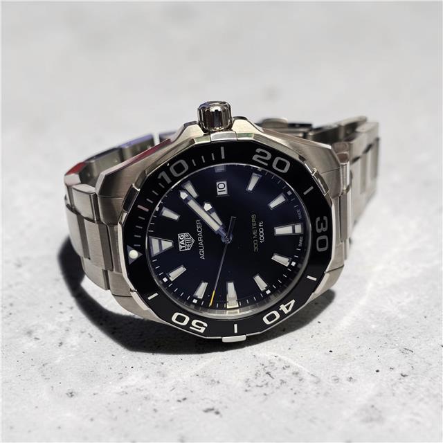 TAG Heuer Aquaracer 300 meters diving watch with black dial, stainless steel bracelet, and rotating bezel.