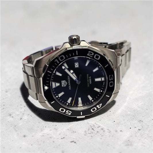 TAG Heuer Aquaracer 300 meters diving watch with black dial, stainless steel bracelet, and rotating bezel.