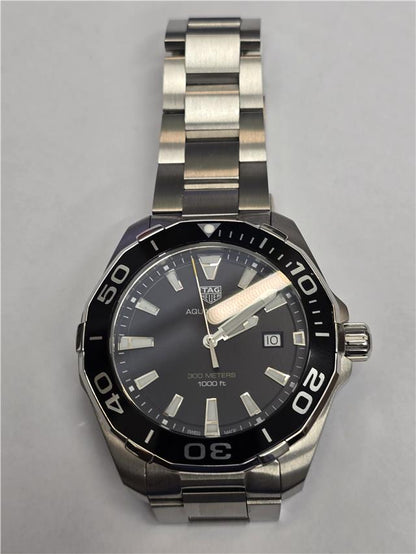 TAG Heuer Aquaracer 300 meters diving watch with black dial, stainless steel band, and unidirectional bezel.