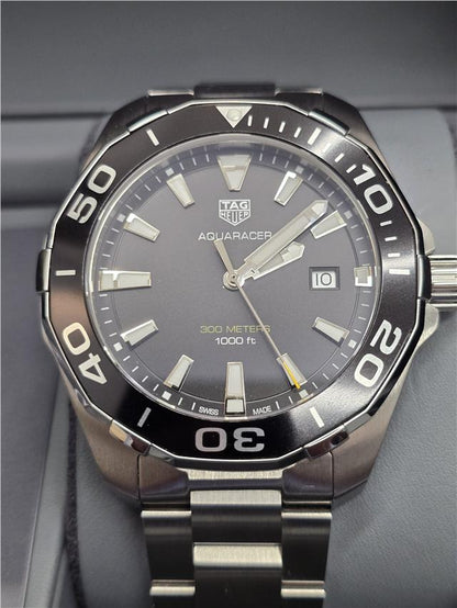 TAG Heuer Aquaracer 300 meters diving watch with black dial, stainless steel band, and unidirectional bezel.
