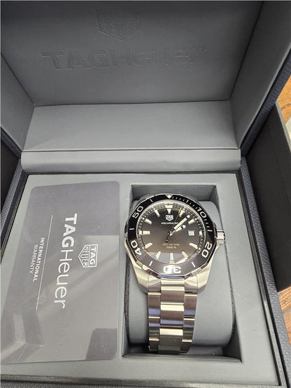 TAG Heuer Aquaracer 300 meters diving watch with black dial and stainless steel bracelet, featuring luminous hands and bezel.