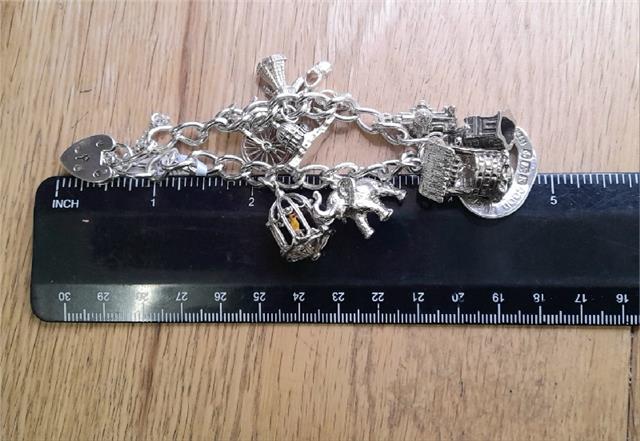 925 silver charm bracelet weighing 53.6g and measuring 7 inches, featuring intricate charm details and a secure clasp.