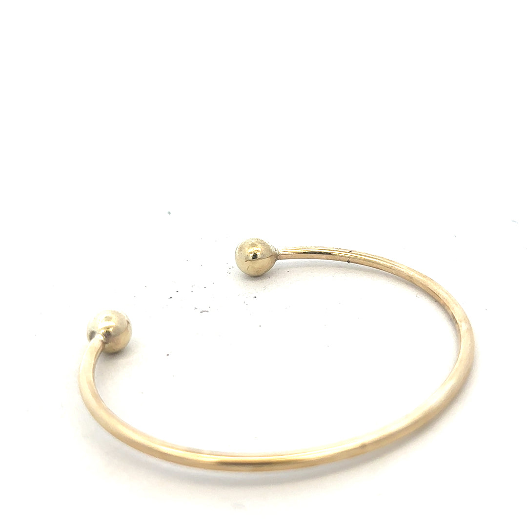 9ct yellow gold bangle weighing 12.7g, unbranded, with a smooth polished finish and rounded shape, displayed on a white background.
