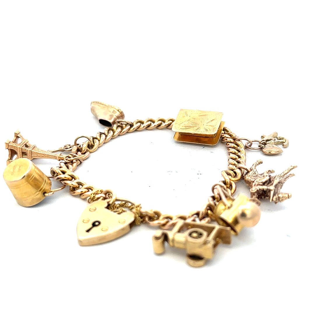 9ct yellow gold charm bracelet with detailed charms, weighs 28.1g, showcasing intricate design and craftsmanship.
