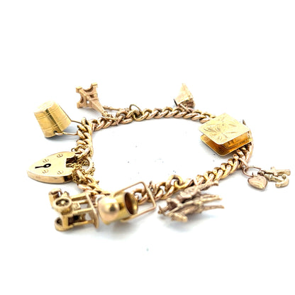 9ct yellow gold charm bracelet weighing 28.1g with detailed charms, unbranded, showcasing its elegant design and polished finish.