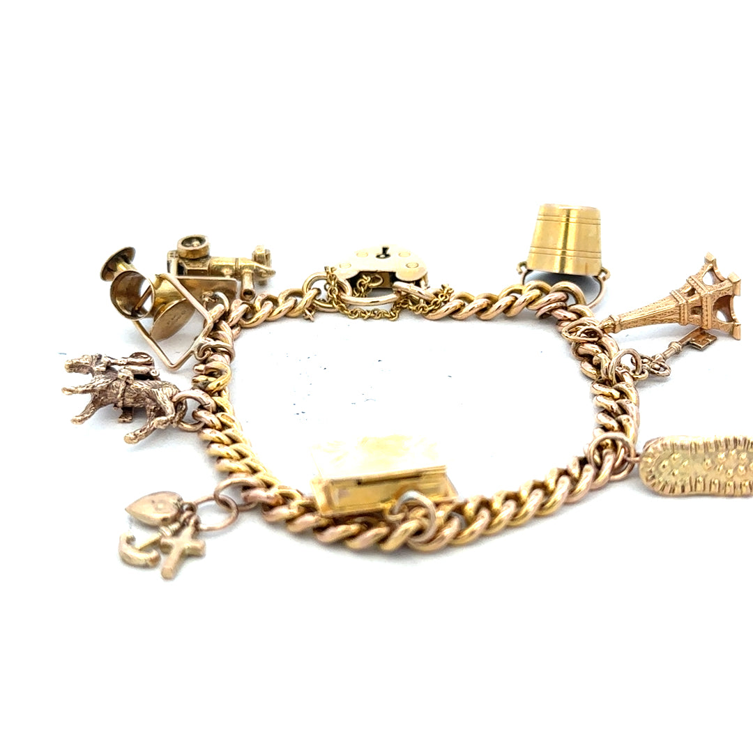 9ct yellow gold charm bracelet weighing 28.1g with intricate charms, unbranded, featuring detailed gold craftsmanship.