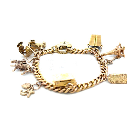9ct yellow gold charm bracelet weighing 28.1g with intricate charms, unbranded, featuring detailed gold craftsmanship.