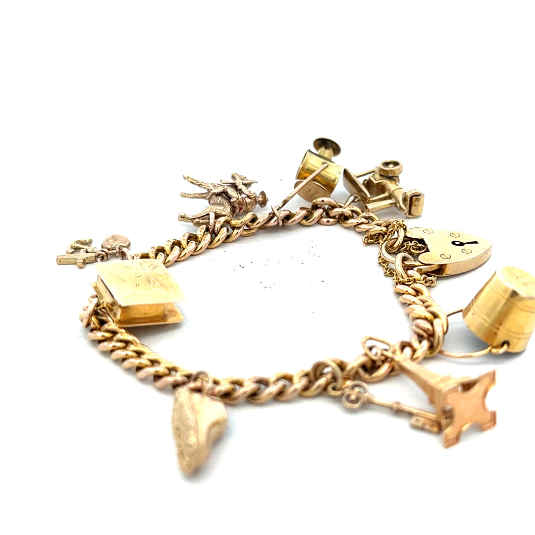 9ct yellow gold charm bracelet with intricate designs, weighing 28.1g, featuring various decorative charms and a secure clasp.