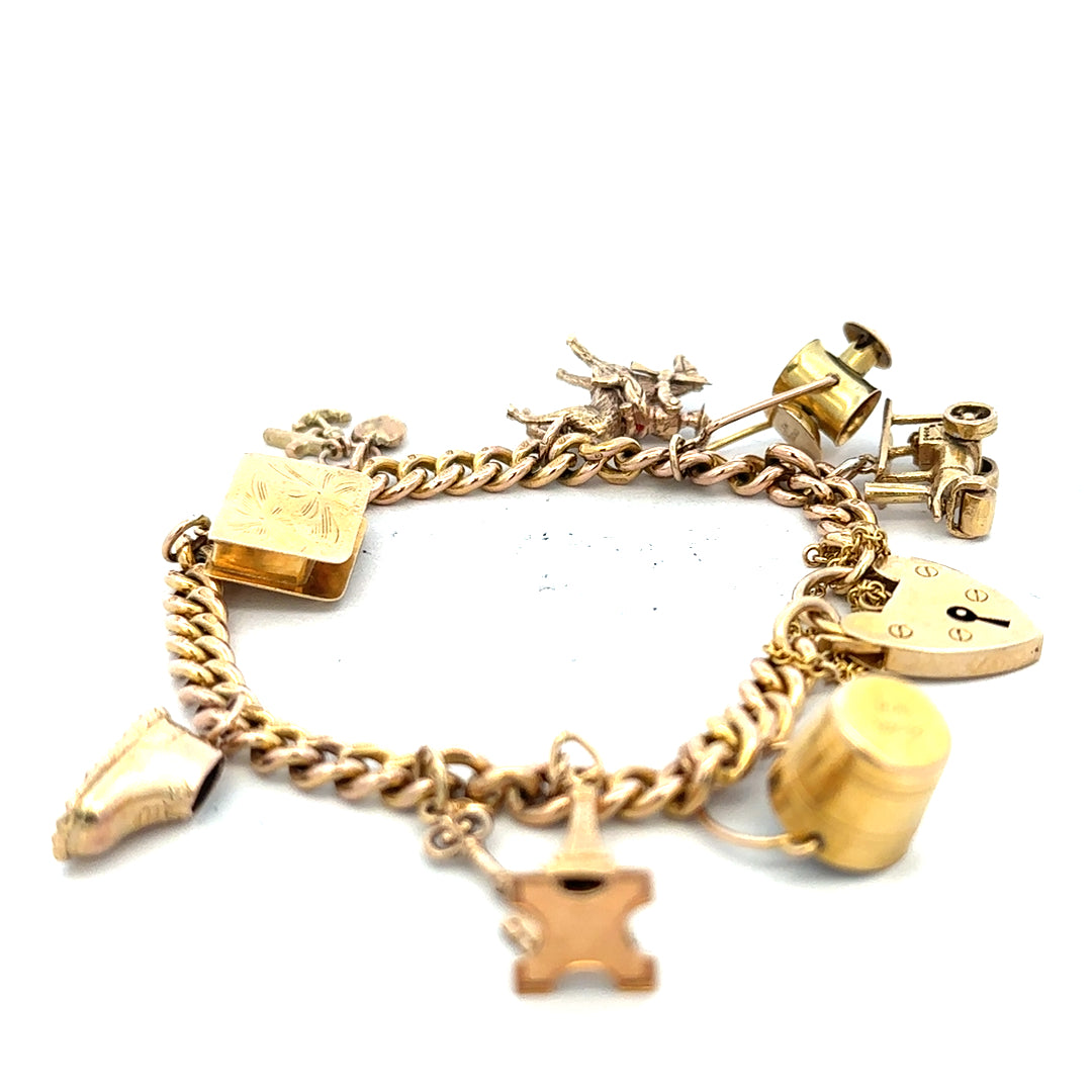 9ct yellow gold charm bracelet weighing 28.1g with intricate charms, unbranded jewelry piece on a plain background.