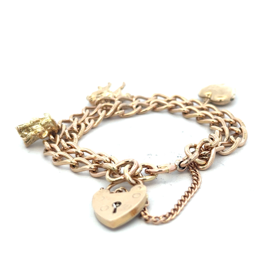 9ct yellow gold charm bracelet with intricate designs, weighs 28.5g, featuring various decorative charms and links.
