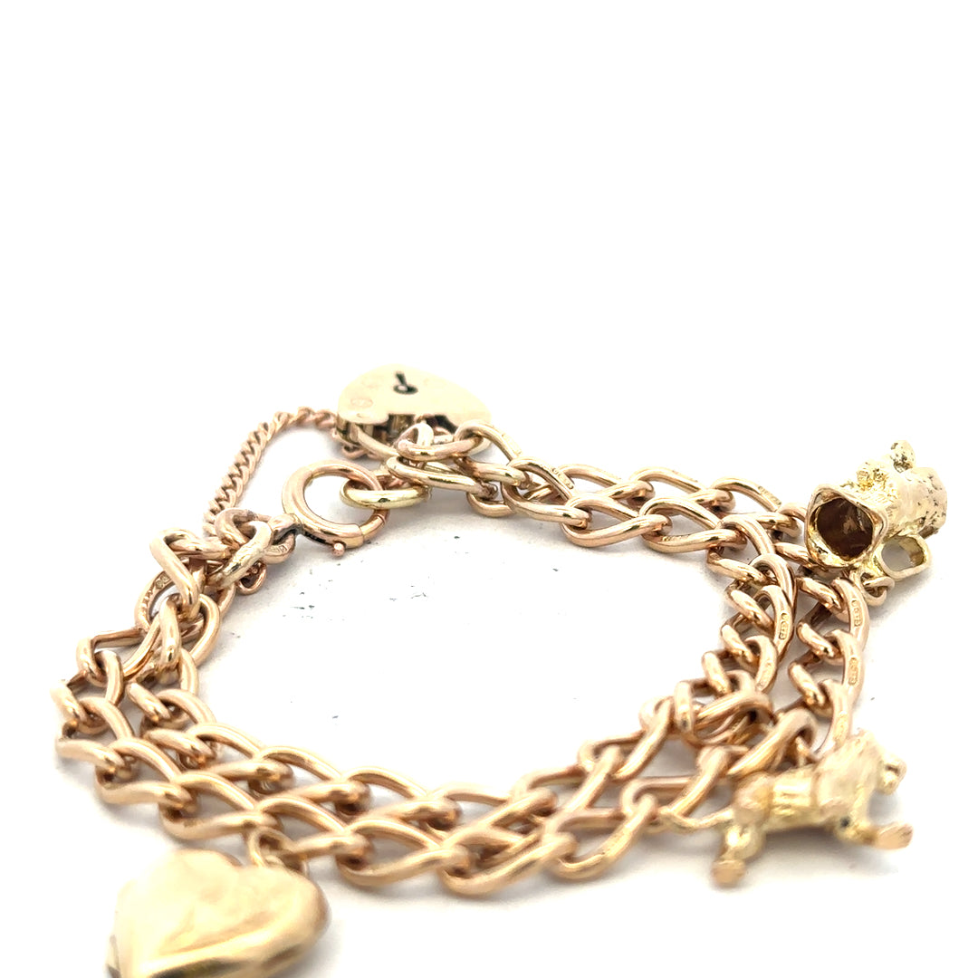 9ct yellow gold charm bracelet weighing 28.5g, featuring various decorative charms, unbranded, with a secure clasp.