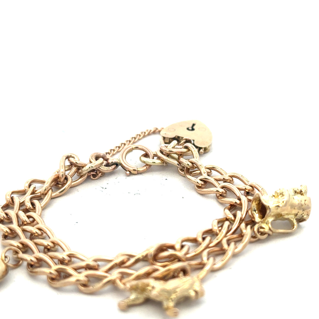 9ct yellow gold charm bracelet with intricate designs, weighing 28.5 grams, featuring multiple charms on a delicate chain.