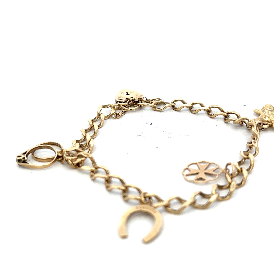 9ct yellow gold charm bracelet weighing 9.9 grams, featuring various decorative charms and a secure clasp.