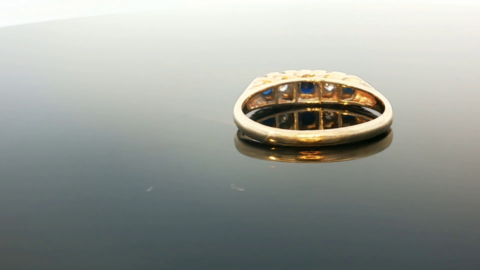 9ct yellow gold ring featuring diamonds and sapphires, showcasing a sparkling gemstone design and elegant craftsmanship.