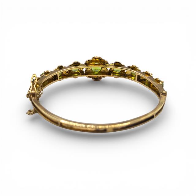 9ct yellow gold peridot bangle with green gemstone accents, showcasing a sleek and elegant jewelry design.