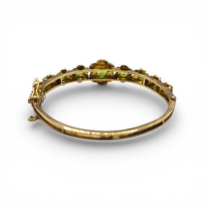 9ct yellow gold peridot bangle with green gemstone accents, showcasing a sleek and elegant jewelry design.