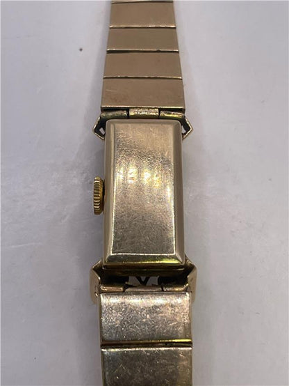 9ct yellow gold ruby and diamond watch with a sleek design, featuring a gold bracelet and elegant face.