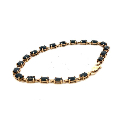 9ct yellow gold sapphire bracelet with intricate design, featuring vibrant blue sapphires and delicate gold links.
